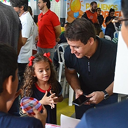 Pai e filha visitando uma barraca durante feira do projeto Pequenos Empreendedores da Escola Luz