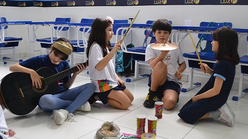 Crianças manuseando e criando instrumentos musicais durante aula na Escola Luz