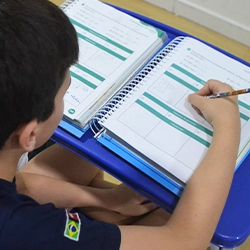 Aluno escrevendo durante aula na Escola Luz