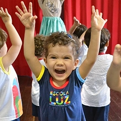Criança feliz com os braços para cima durante aula na Escola Luz