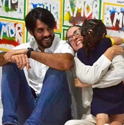 Pais abraçando uma criança durante um projeto na Escola Luz