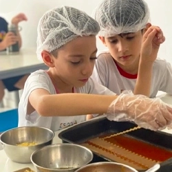 Alunos da Escola Luz fazendo uma lasanha durante a aula de Culinária
